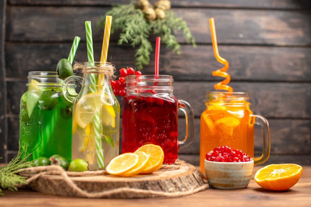 front-close-view-organic-fresh-juices-bottles-served-with-tubes-fruits-wooden-cutting-board-brown-table